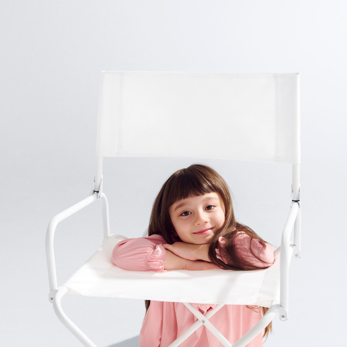 白いyocabito 折りたたみチェア CEREMONYと笑顔の子供。シンプルでおしゃれな背もたれのデザインをアップで。