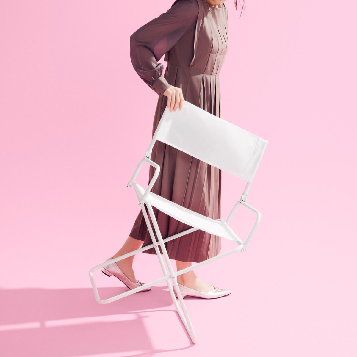 おしゃれな女性が軽々と運ぶyocabitoの白い折りたたみチェアCEREMONY。シンプルなデザインで持ち運びもスマートに。